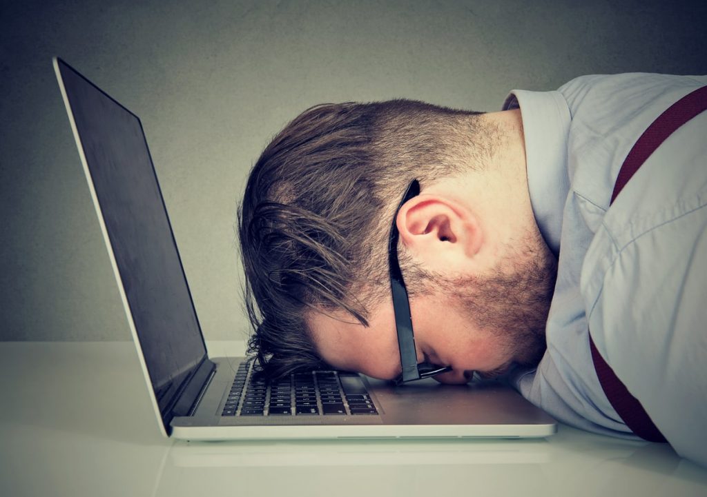 man resting his head on the laptop keyboard